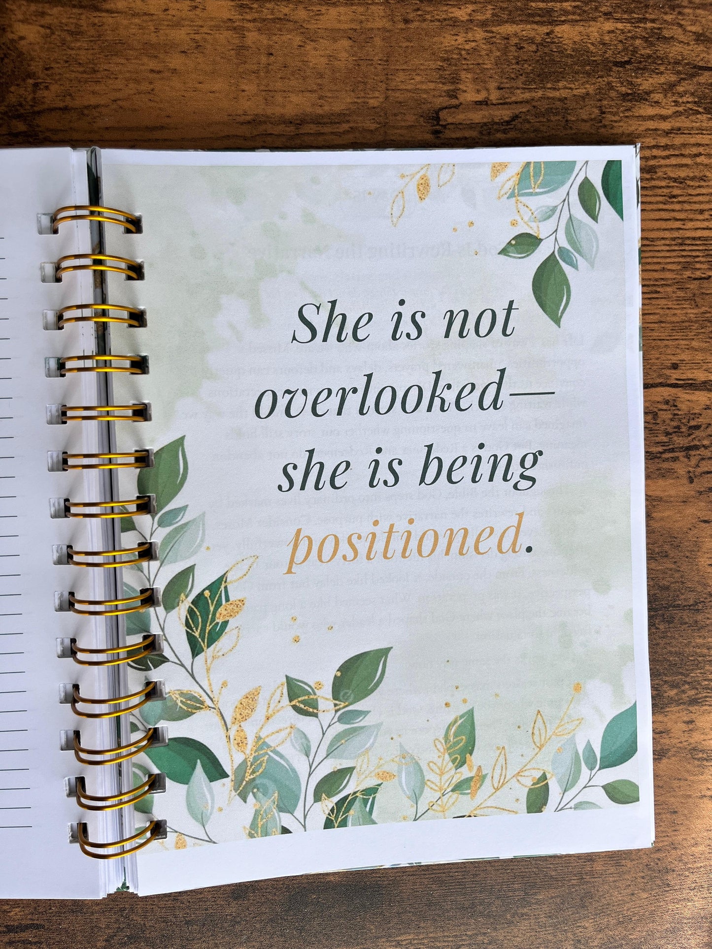 Spiral-bound notebook with motivational quote on a wooden surface